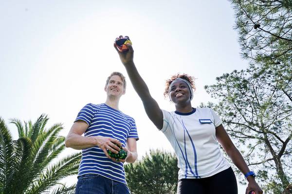 Zwei Personen, eine Frau und ein Mann, spielen mit bunten magischen Würfeln in einem Garten.