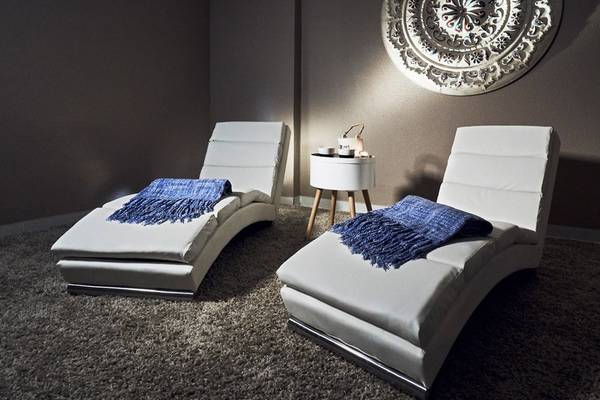 Zwei weiße Sessel im Zimmer mit blauen Decken und einem kleinen Tisch dazwischen.