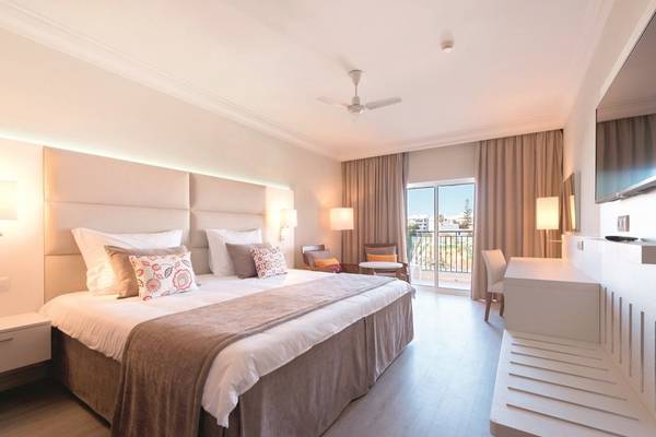 Schlafzimmer im Falesia Hotel in Algarve mit Doppelbett, Nachttischen und Balkon.