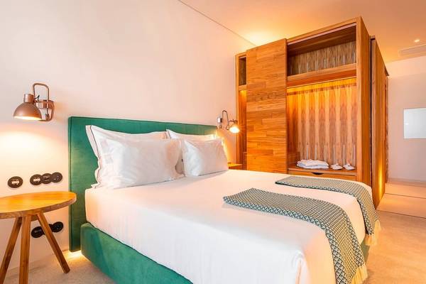 3HB Faro Hotelzimmer mit Bett, Nachttisch und Wandbeleuchtung.
