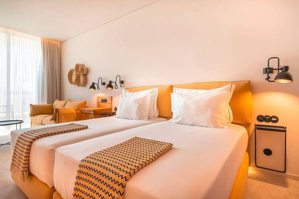 Doppelbett-Zimmer im 3HB Faro Hotel mit gelben Kopfteilen und weißen Laken.