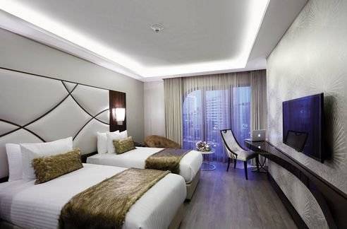 Doppelzimmer im DoubleTree by Hilton Istanbul Esentepe mit zwei Betten, Fernseher und Arbeitsbereich.