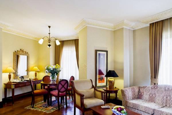 Wohnbereich des Eresin Sultanahmet Hotels mit Möbeln, Tisch, Sofa, Lampen und Gemälden.