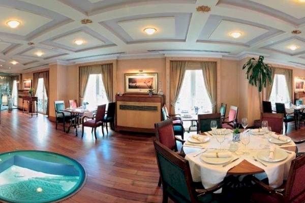 Innenansicht des Speisesaals im Eresin Sultanahmet Hotel mit runden Tisch, weiße Tischdecke, und grüner Boden.