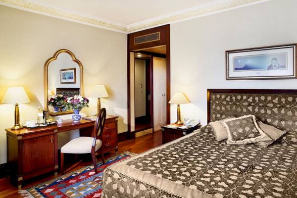 Schlafzimmer im Eresin Sultanahmet Hotel mit Bett, Nachttischen, Stühlen und Blumenvase.