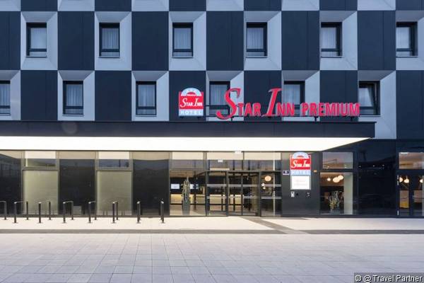 Außenansicht des Star Inn Hotel Premium Hauptbahnhof in Wien mit roter Beschilderung.