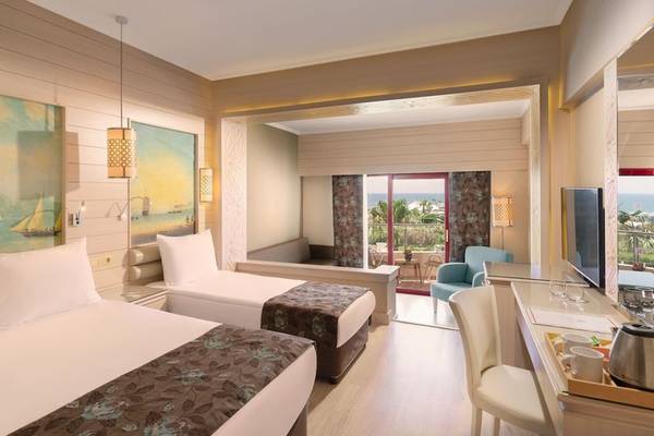 Doppelzimmer mit Meerblick im Kaya Belek Hotel mit zwei Betten, Schreibtisch und Meersicht.