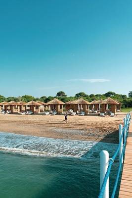 Außenbereich des Rixos Premium Belek Hotels mit vielen strohgedeckten Häuschen am Strand