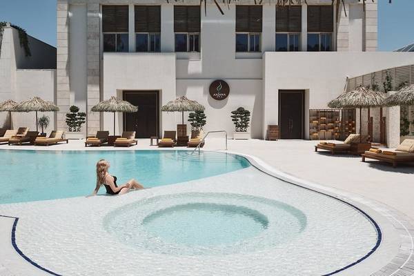 Eine Frau sitzt im Whirlpool des Rixos Premium Belek Hotels neben einem runden Pool.