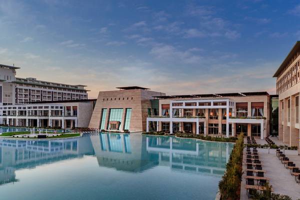 Außenansicht des Rixos Premium Belek Hotels mit großen Pool und moderner Architektur.