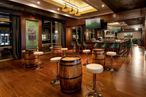 Innenansicht der Bar im Rixos Premium Belek Hotel mit hölzernem Boden und grünen Stühlen.