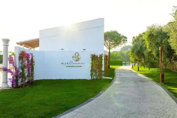 Eingang des Rixos Premium Belek Hotels mit weißem Gebäude und bunten Blumen.