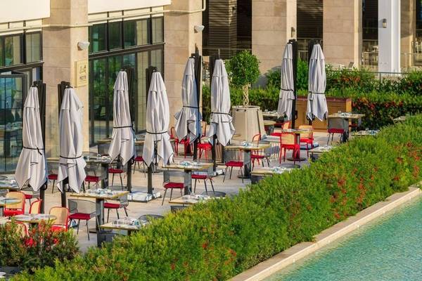 Außenterrasse des Rixos Premium Belek Hotels mit Tischen, Stühlen und Schirmen