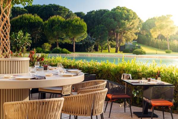 Außenbereich des Rixos Premium Belek Hotels mit Sitzgelegenheiten und Tischen vor einem Pool.