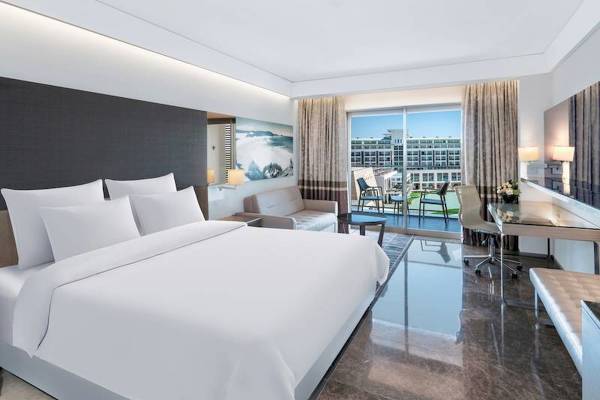 Schlafzimmer im Rixos Premium Belek Hotel mit großem Bett, Couch, Schreibtisch und Terrassenblick.