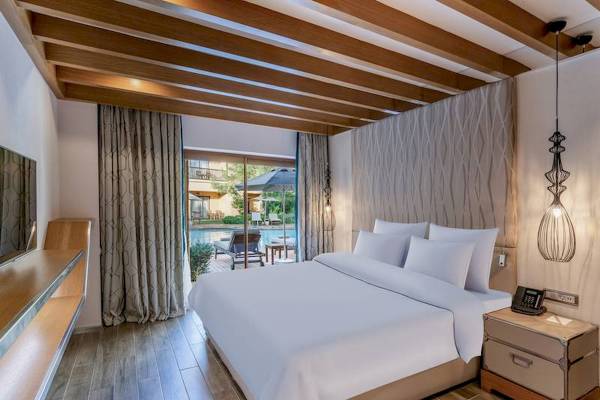Hotelzimmer mit Poolblick im Rixos Premium Belek, mit bequemem Bett, Telefon und Aussicht auf Pool und Terrasse.