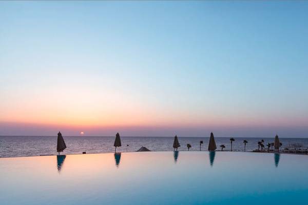 Sonnenuntergang am Pool des Pickalbatros Citadel Resorts mit Blick auf das Meer und Palmen.