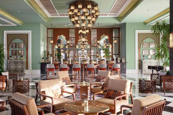Lobby des Steigenberger Resort Alaya mit einer großen Kronleuchter, Holzstühlen und Tischen.