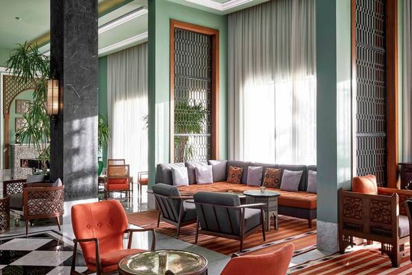 Ein modernes Hotellobby mit Sitzbereich, Sofas, Sesseln, Tisch, Teppich, und Pflanzen.