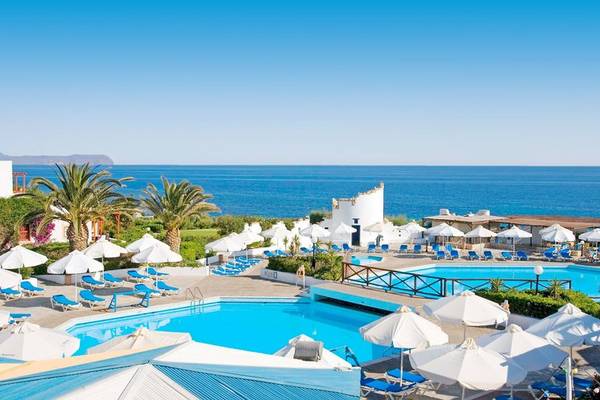Außenbereich des Mitsis Cretan Village Resorts mit Swimmingpools, Sonnenliegen und Sonnenschirmen.