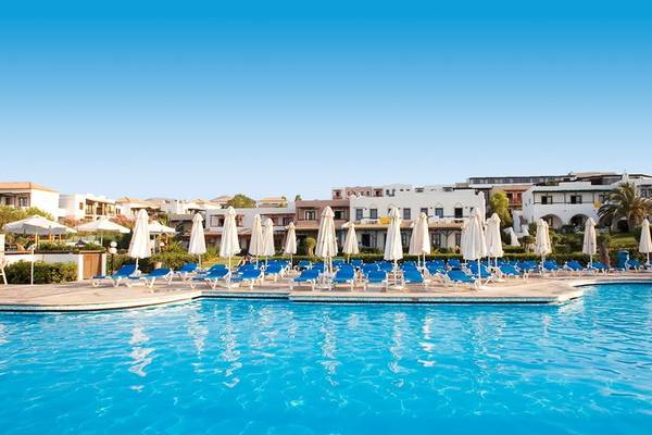 Außenpoolbereich des Mitsis Cretan Village Hotels mit weißen Liegestühlen und Sonnenschirmen