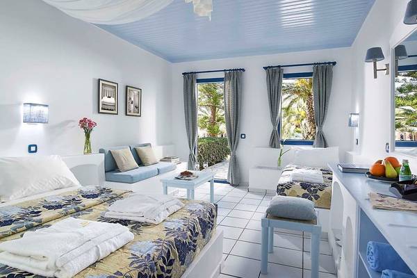 Schlafzimmer im Mitsis Cretan Village Hotel mit weißen Möbeln, blauer Decke und offenem Fenster.