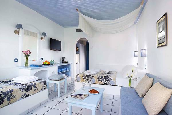 Innenansicht eines Zimmers im Mitsis Cretan Village Hotel mit zwei Betten, einem Sofa, einer Couch und einem Tisch.