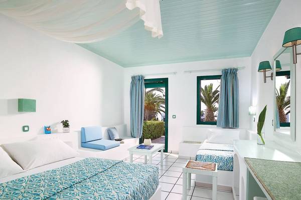 Doppelzimmer im Mitsis Cretan Village Hotel mit zwei Betten, weißem Interieur und blauen Akzenten.