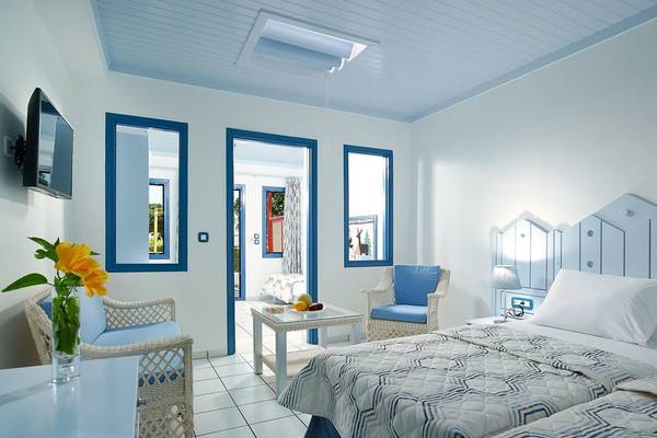Doppelzimmer im Mitsis Cretan Village Hotel mit blauen Akzenten und weißen Möbeln.