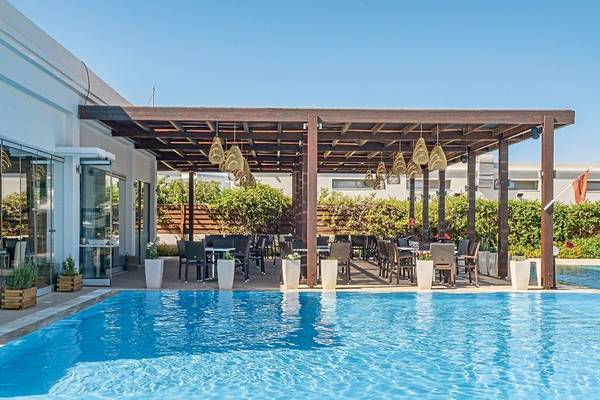 Außenbereich des Asterias Beach Resorts mit Pool, Pergola und Sitzplätzen.