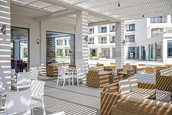 Loungebereich des Asterias Beach Resort mit weißen Möbeln und einem weißen Pergoladach.