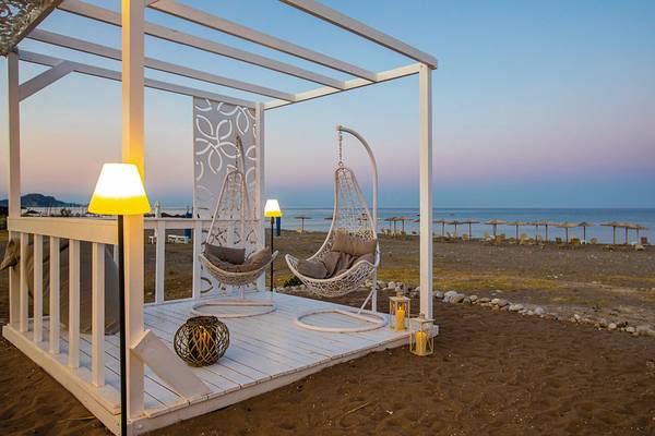 Terrasse mit Sesseln am Strand im Asterias Beach Resort mit Blick auf das Meer und den Sonnenuntergang