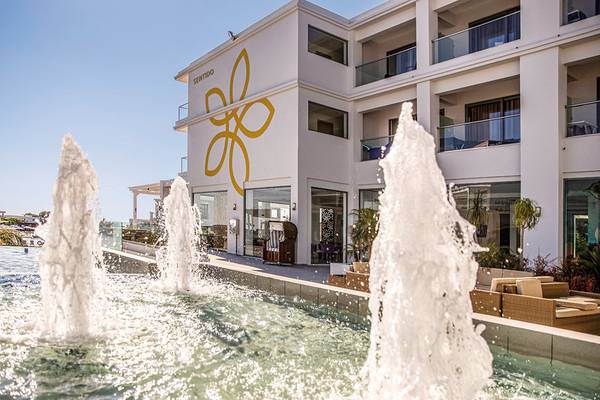 Außenansicht des Asterias Beach Resorts mit einem großen Brunnen vor dem Gebäude.