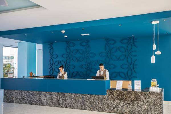 Rezeption im Asterias Beach Resort mit blauer Wandgestaltung und zwei Mitarbeitern