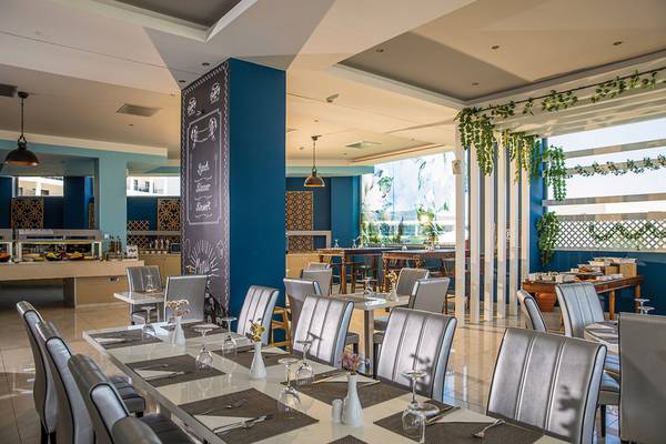 Innenansicht des Restaurants im Asterias Beach Resort mit blauen Säulen und modernen Möbeln.