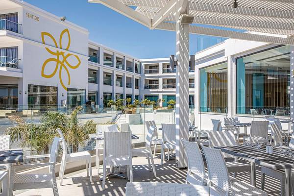 Außenterrasse des Asterias Beach Resorts mit weißen Stühlen und Tischen.