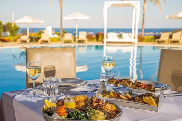 Tisch am Pool im Asterias Beach Resort Hotel mit Getränken und Speisen.