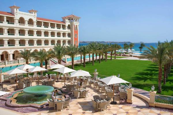 Außenbereich des Baron Palace Sahl Hasheesh Hotels mit Swimmingpool und Palmen.