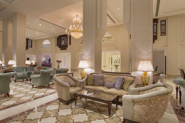 Lobby des Baron Palace Sahl Hasheesh Hotels mit Sofas, Lampen und einem Kronleuchter.