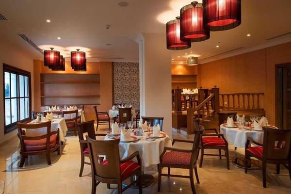Innenansicht des Restaurants im Baron Palace Sahl Hasheesh Hotel mit gedeckten Tischen und roten Lampen.