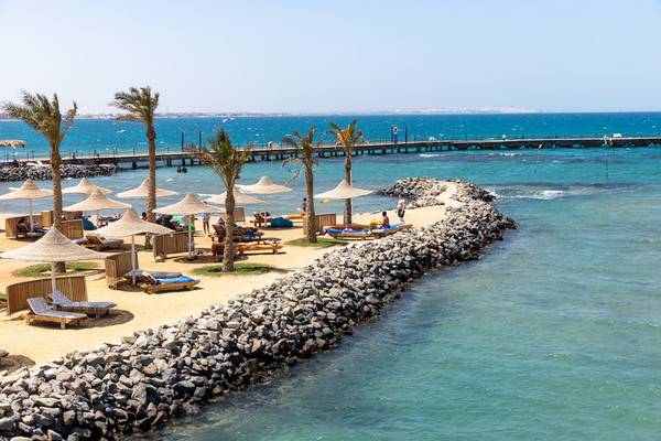 Strand am Desert Rose Resort mit Palmen und Liegestühlen, Blick auf das Meer
