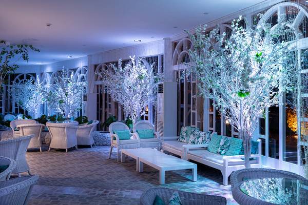 Loungebereich im Desert Rose Resort mit weißen Möbeln und blauen Kissen, dekoriert mit weißen leuchtenden Bäumen.