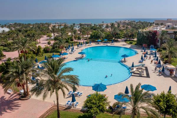 Luftaufnahme des großen Swimmingpools im Desert Rose Resort mit Sonnenschirmen und Palmen