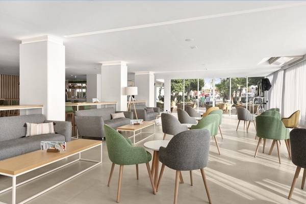 Lobbybereich des THB Gran Playa Hotels mit grauen Sofas und bunten Stühlen.