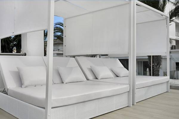 Loungebereich des THB Gran Playa Hotels mit weißen Sonnenliegen und Vorhängen.