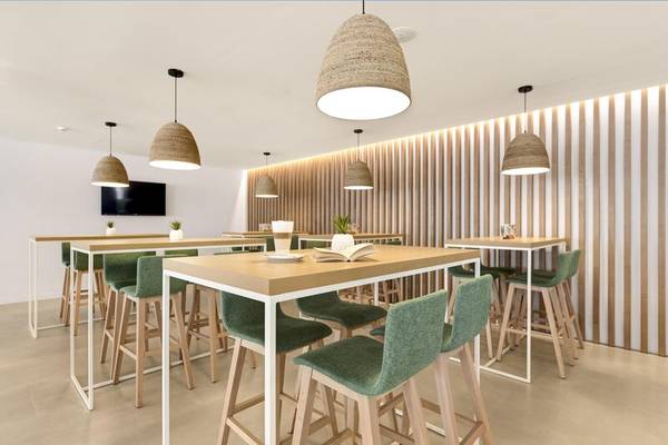 Innenraumdesign des THB Gran Playa Hotel mit Tischen, Stühlen und Wanddekoration.