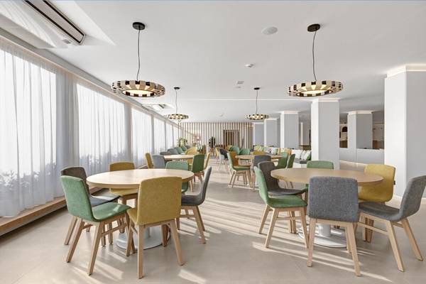 Innenraum des THB Gran Playa Hotels mit runden Tischen und Stühlen, weißer Decke, und hängenden Leuchten.
