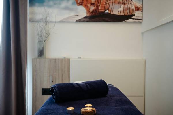 Massage-Raum im THB Gran Playa Hotel mit blauer Bettdecke, Kerzen und Kunstwerk an der Wand.