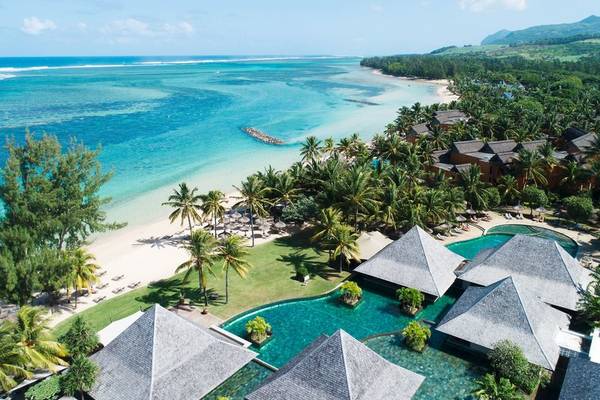 Außenansicht des Heritage Awali Golf & Spa Resorts mit Blick auf einen Pool, eine tropische Landschaft und einen Strand.
