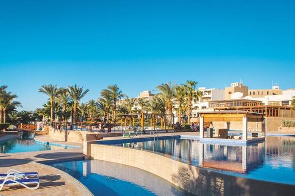 Poolbereich des Fort Arabesque Resorts mit Loungeliegen und Gebäuden im Hintergrund.